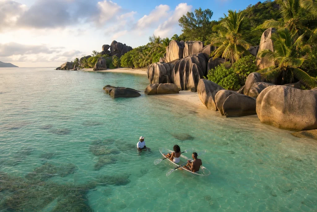 Clear kayakers exploring the shallow lagoon and granite boulders of Anse Source d’Argent.